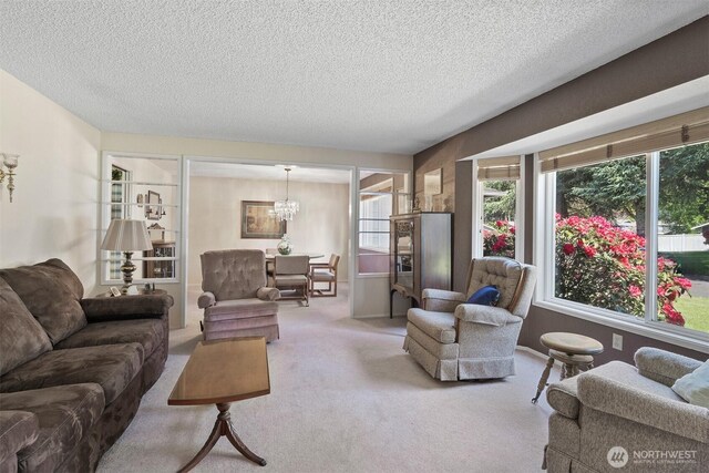 living area with carpet flooring, a textured ceiling, a notable chandelier, and plenty of natural light