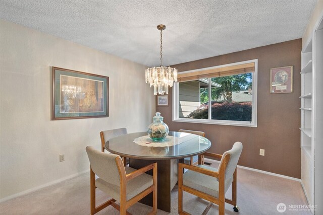dining room with a textured ceiling, baseboards, a chandelier, and carpet