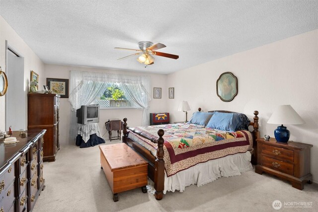 bedroom featuring ceiling fan, a textured ceiling, and light colored carpet
