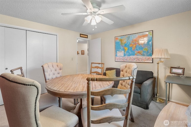 dining area with a ceiling fan, a textured ceiling, baseboards, and carpet