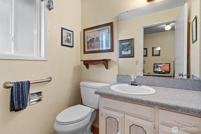 half bath featuring vanity and toilet