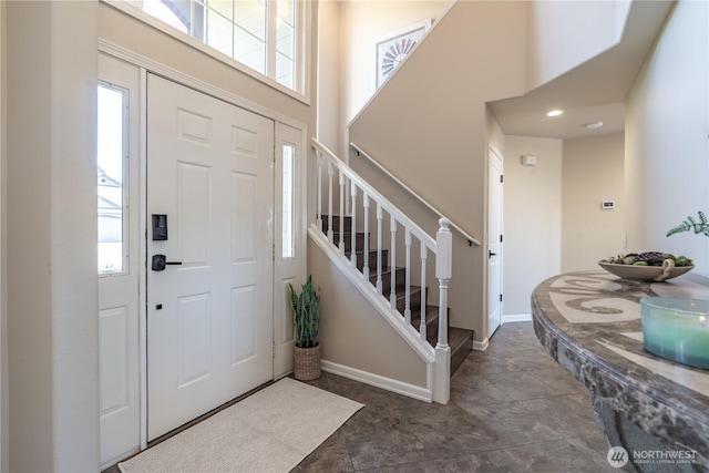 entryway with a high ceiling, a healthy amount of sunlight, and stairway