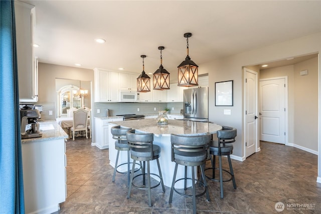 kitchen featuring white cabinetry, appliances with stainless steel finishes, hanging light fixtures, and light stone counters
