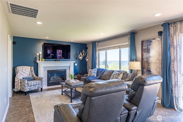 living area with a tiled fireplace, baseboards, recessed lighting, and visible vents