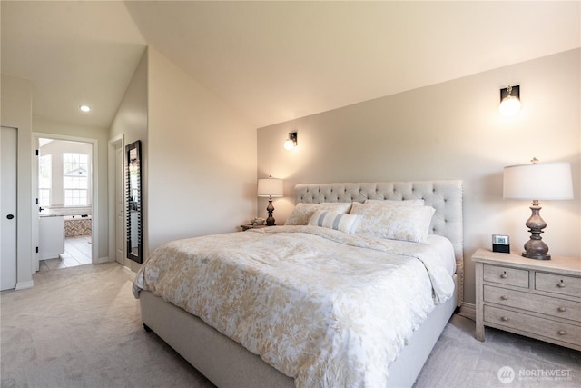 bedroom featuring baseboards, light colored carpet, ensuite bathroom, and vaulted ceiling
