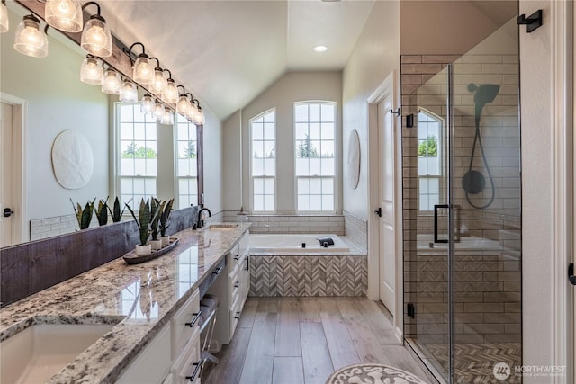 full bathroom with double vanity, a bath, a shower stall, a sink, and wood-type flooring