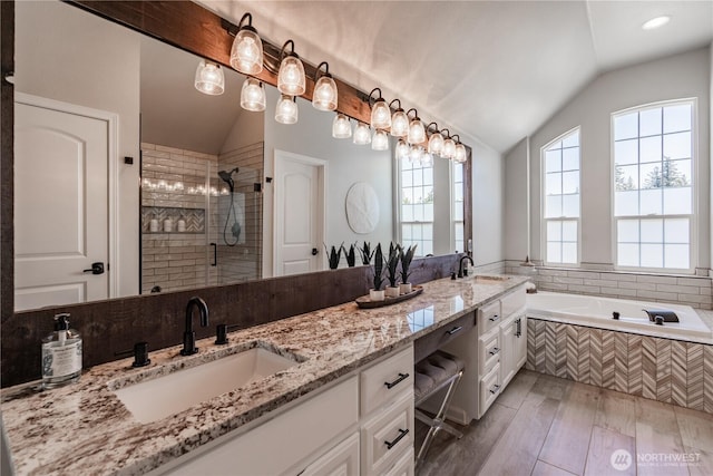 bathroom with double vanity, a sink, lofted ceiling, and tiled shower