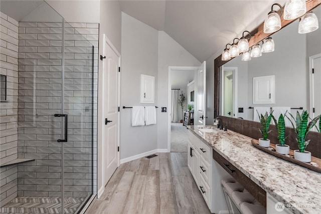 bathroom featuring vaulted ceiling, a shower stall, wood finished floors, and vanity