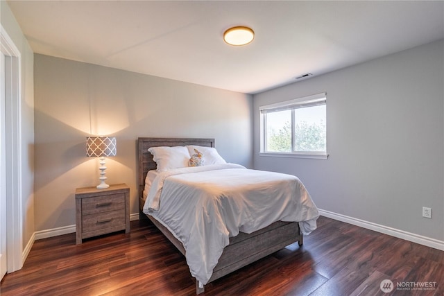 bedroom with baseboards, wood finished floors, and visible vents