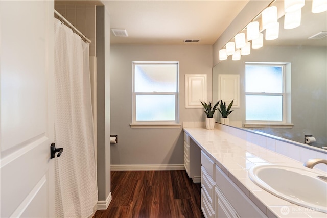 bathroom featuring a healthy amount of sunlight, vanity, baseboards, and wood finished floors