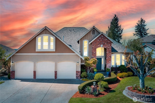 traditional home featuring roof with shingles, brick siding, a front lawn, concrete driveway, and an attached garage
