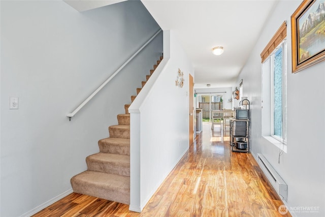 interior space with baseboards, a baseboard heating unit, and wood finished floors