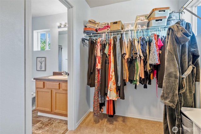 walk in closet featuring light colored carpet and a sink