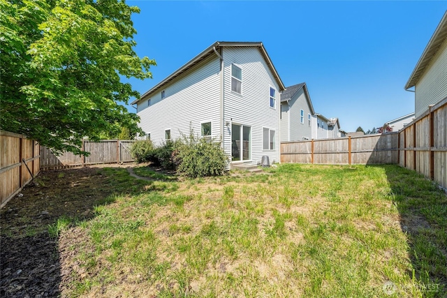 rear view of house featuring a lawn and a fenced backyard