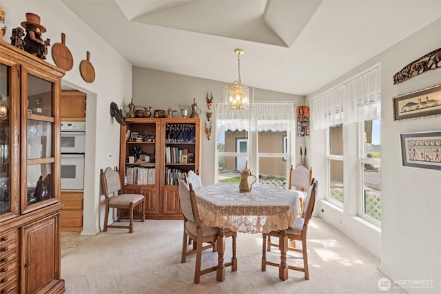 dining area featuring a notable chandelier, light carpet, and lofted ceiling