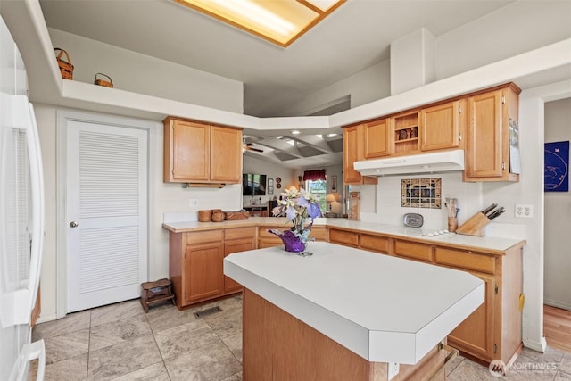 kitchen featuring a center island, light countertops, and under cabinet range hood