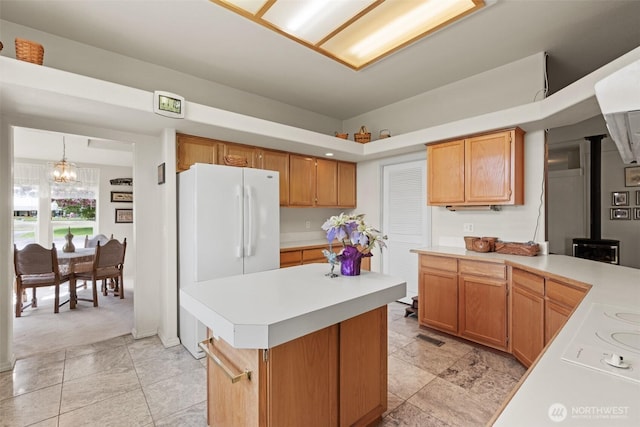 kitchen featuring light countertops, an inviting chandelier, freestanding refrigerator, and a wood stove