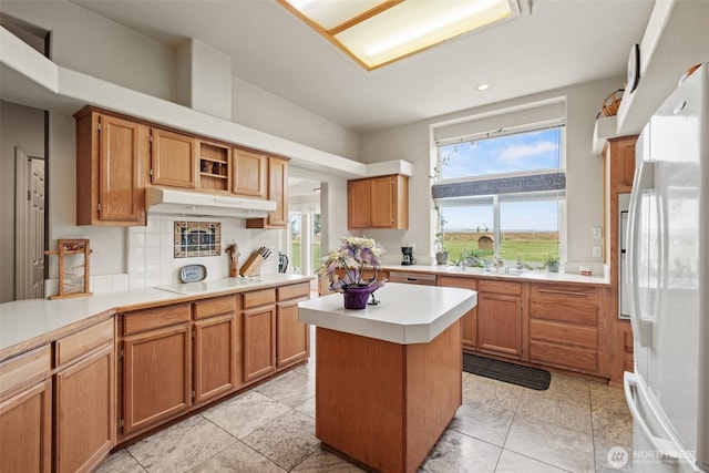 kitchen with white appliances, light countertops, recessed lighting, under cabinet range hood, and a kitchen island
