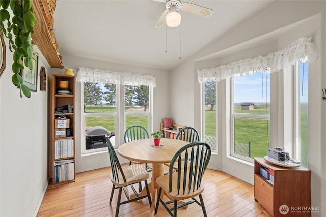 dining room featuring baseboards, a ceiling fan, vaulted ceiling, and light wood-type flooring