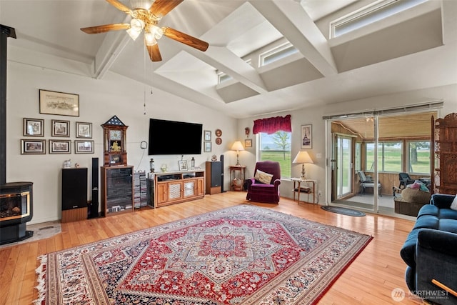 living room with light wood-style floors, plenty of natural light, a ceiling fan, and a wood stove