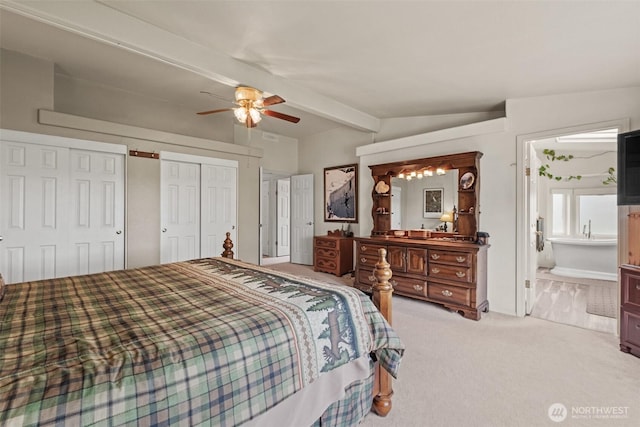 bedroom featuring ceiling fan, light carpet, beam ceiling, multiple closets, and ensuite bathroom