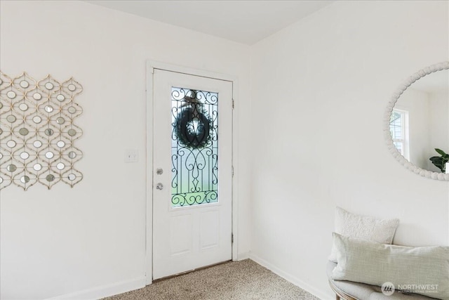 foyer entrance with baseboards and light carpet