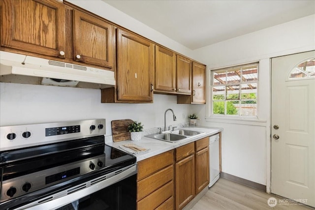 kitchen featuring stainless steel electric range, a sink, dishwasher, light countertops, and under cabinet range hood