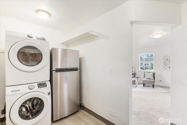 laundry room with baseboards, stacked washer and clothes dryer, and laundry area