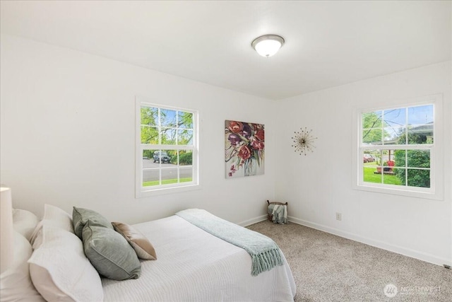 carpeted bedroom featuring baseboards and multiple windows