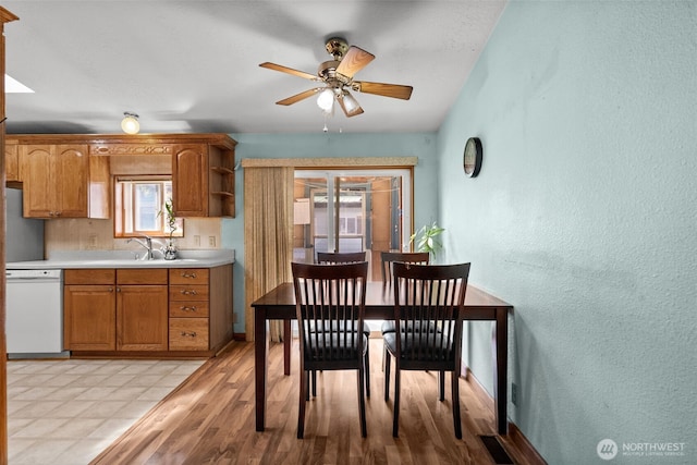 dining space with a textured wall, a ceiling fan, light wood-style flooring, and visible vents