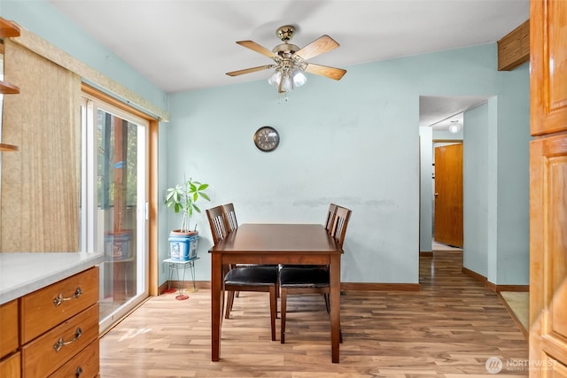dining space with baseboards, light wood-style flooring, and ceiling fan