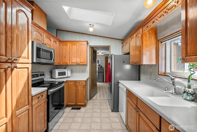 kitchen featuring crown molding, a sink, stainless steel appliances, light floors, and a skylight