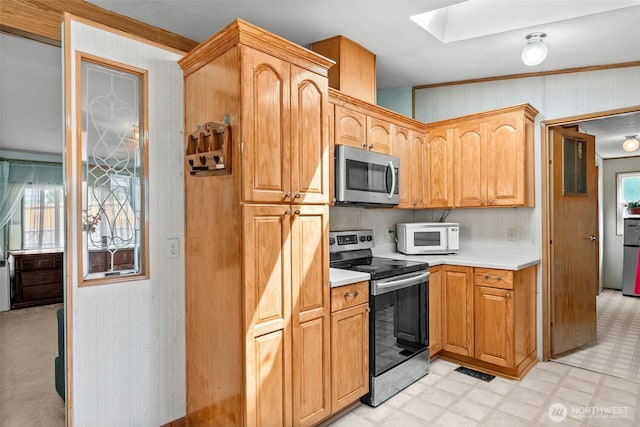 kitchen with light countertops, stainless steel appliances, light floors, a skylight, and visible vents