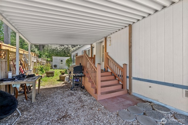 view of patio with area for grilling, visible vents, an outbuilding, fence, and a storage unit