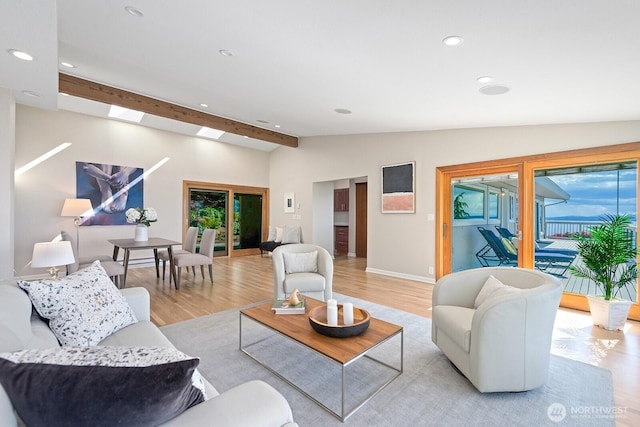 living room with light wood finished floors, recessed lighting, a skylight, and baseboards