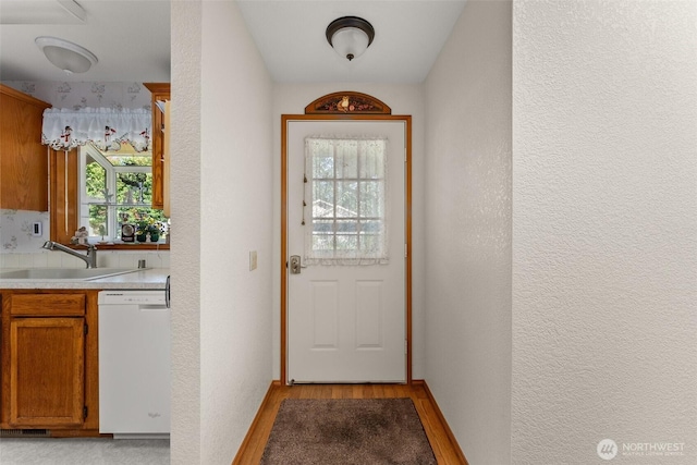 entryway featuring light wood-style floors, a sink, and a textured wall