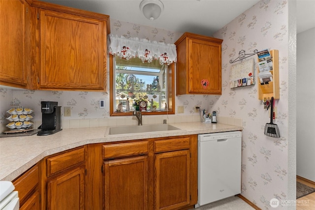 kitchen featuring light countertops, wallpapered walls, a sink, and dishwasher