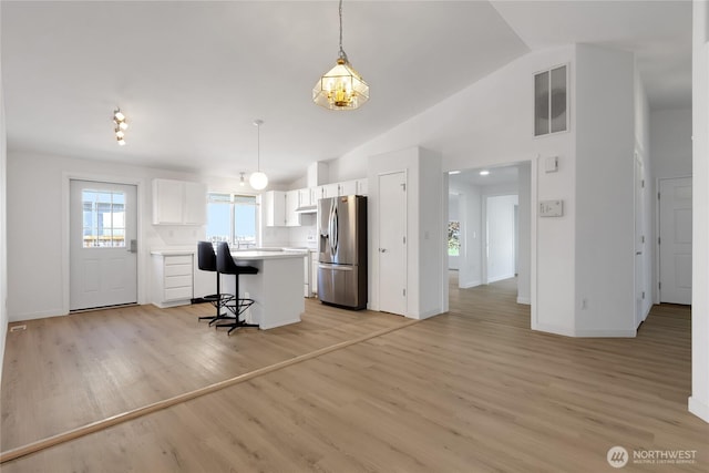 22516 45th Ave E, Spanaway, WA 98387 - kitchen with light countertops, white cabinetry, lofted ceiling, and stainless steel fridge with ice dispenser