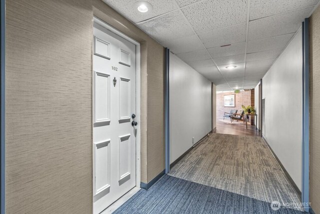 9500 Rainier Ave S Unit 102, Seattle, WA 98118 - hall featuring baseboards, a drop ceiling, and dark colored carpet