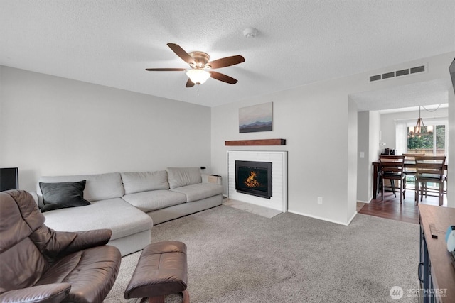 1718 33rd St SE, Auburn, WA 98002 - carpeted living area featuring ceiling fan, a fireplace with flush hearth, a textured ceiling, baseboards, and a chandelier