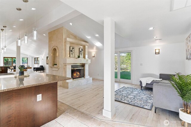 living area featuring a fireplace, vaulted ceiling with beams, light wood-type flooring, baseboards, and recessed lighting