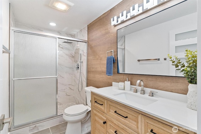 full bath featuring vanity, toilet, a marble finish shower, and wood walls