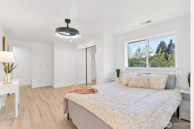 bedroom featuring light wood-type flooring, baseboards, a closet, and visible vents