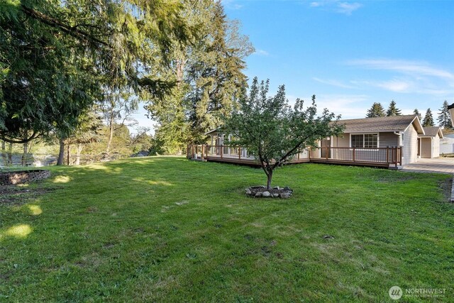 view of yard with a garage, driveway, and a wooden deck