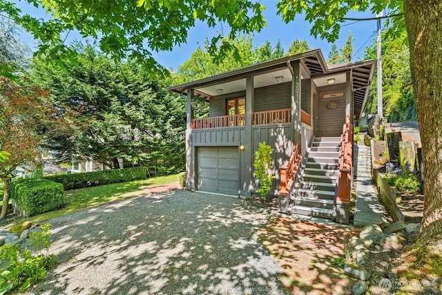 view of front of property featuring a garage, driveway, stairway, and covered porch