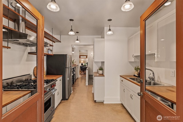 kitchen featuring appliances with stainless steel finishes, hanging light fixtures, a sink, white cabinets, and butcher block countertops