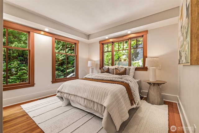 bedroom with baseboards, multiple windows, recessed lighting, and wood finished floors
