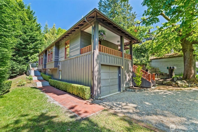 view of side of property featuring a garage, board and batten siding, gravel driveway, and stairway