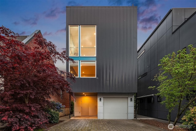 contemporary house with an attached garage and decorative driveway