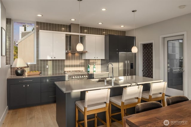 kitchen with hanging light fixtures, a sink, light wood finished floors, stainless steel appliances, and a kitchen bar
